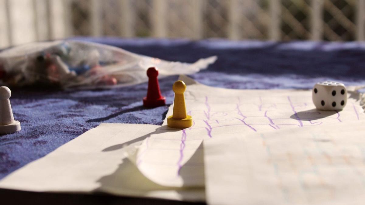 Board game pawns and a die on a paper game board